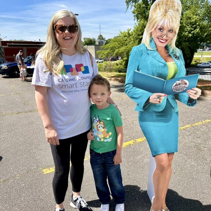 Girl standing with her mother next to a Dolly Parton cutout