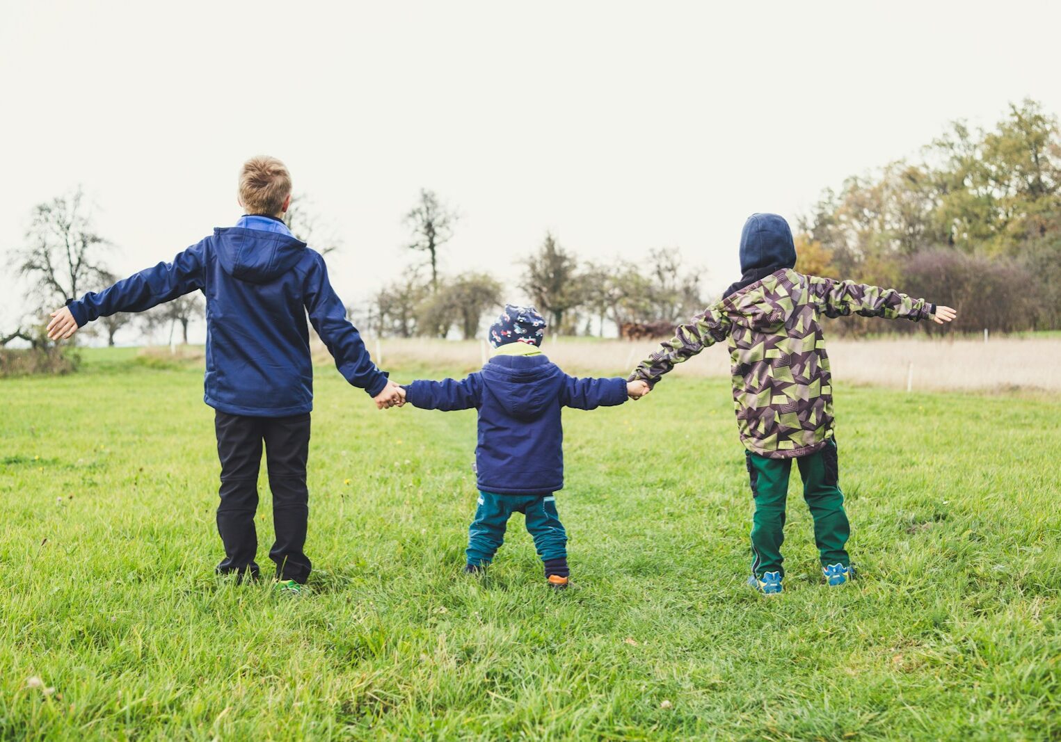 Photo by Markus Spiske three children holding hands standing on grasses